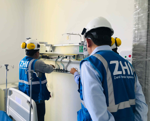 Ingenieros de ZHI instalando panel de cabecera de cama hospitalaria con tomas de gases medicinales